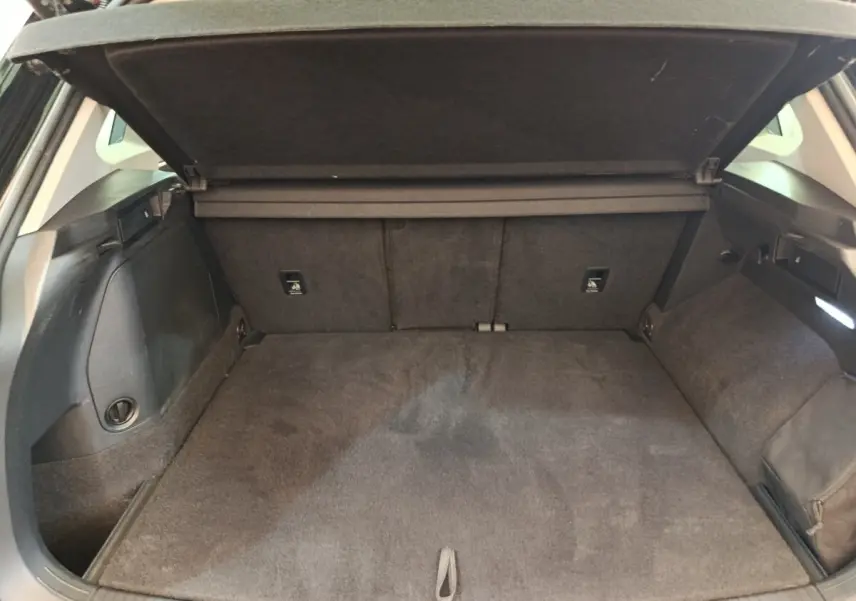 Coffre ouvert du Volkswagen Tiguan noir, vue intérieure arrière montrant l'espace de chargement et la tablette de séparation.