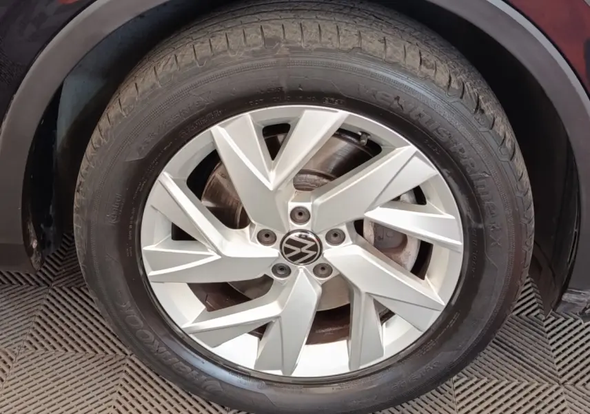 Gros plan sur la jante argentée à design géométrique du Volkswagen Tiguan noir, roue avant droite visible.