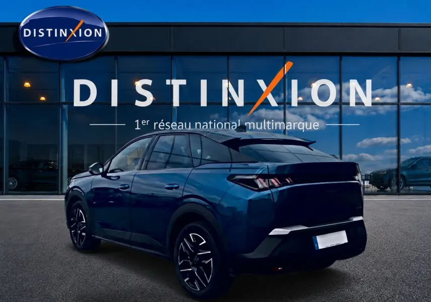 Vue 3/4 arrière d'un Peugeot 3008 bleu 2025 avec jantes alu et becquet arrière, devant une vitrine Distinxion.