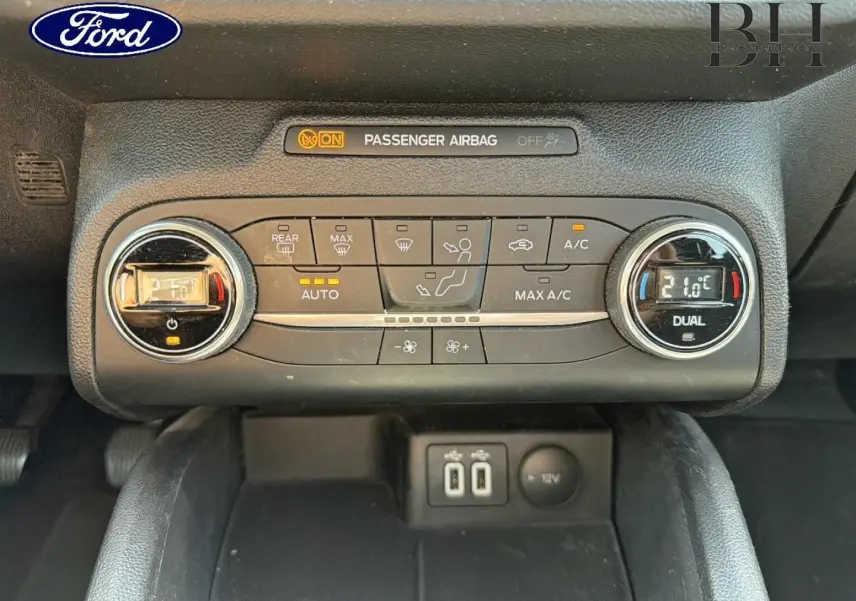 Vue rapprochée de la console centrale de la Ford Focus 1.0 Flexifuel 2021, montrant les commandes de climatisation bi-zone et ports USB.