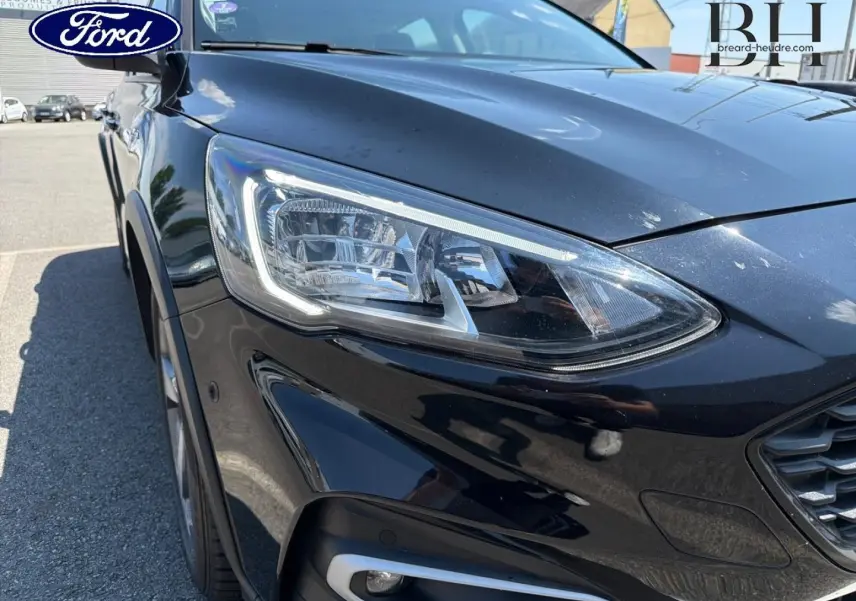 Gros plan sur l'avant droit noir métallisé de la Ford Focus avec son phare LED et calandre visible.