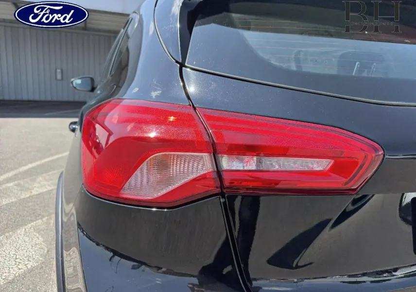 Gros plan sur le feu arrière droit d'une Ford Focus noire Agate métallisé, soulignant la finition et la carrosserie brillante.