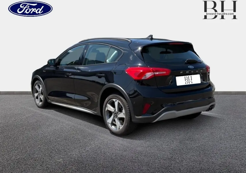 Vue 3/4 arrière gauche d'une Ford Focus 2021 noir Agate métallisé avec jantes alliage et barres de toit.