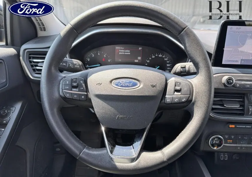 Vue centrée sur le volant cuir noir multifonction de la Ford Focus 1.0 Flexifuel avec tableau de bord et écran tactile visibles.