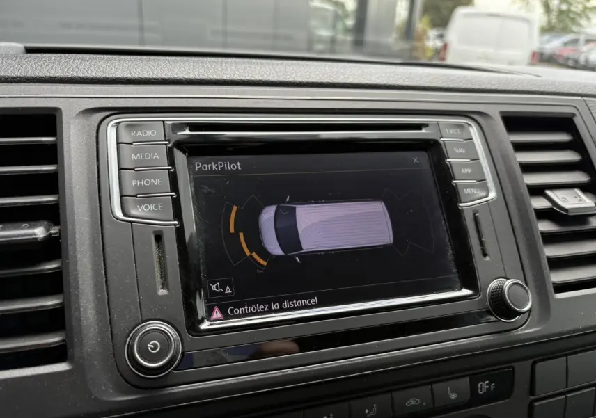 Écran tactile du système ParkPilot dans le tableau de bord du Volkswagen Multivan gris, avec commandes autour.