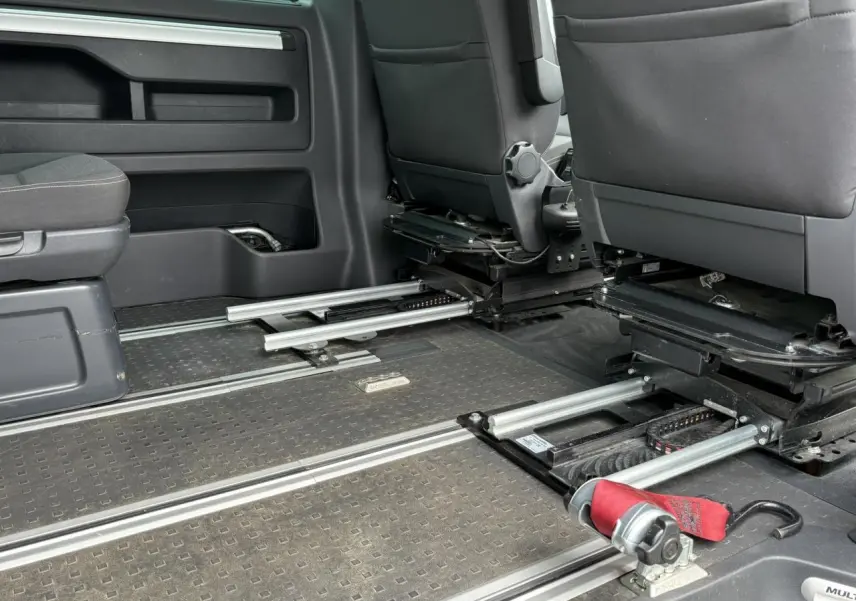 Vue intérieure du Volkswagen Multivan T6 TPMR montrant les rails au sol et les sièges avant gris foncé.