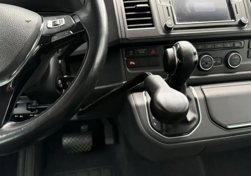 Vue rapprochée de l'intérieur du Volkswagen Multivan T6 2019, montrant le volant cuir et la commande de boîte automatique avec adaptation TPMR.