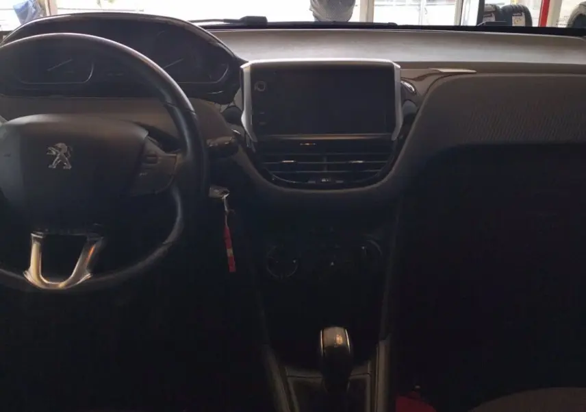 Vue intérieure du tableau de bord et volant noir d'une Peugeot 208 1.6l HDi 75 ch de 2023, avec écran central éteint.