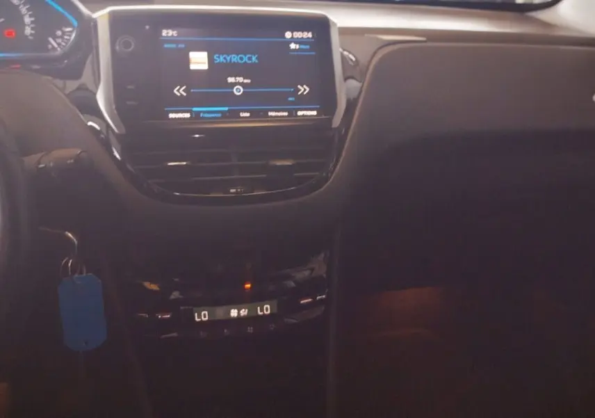 Intérieur noir de la Peugeot 208 2023, vue centrale du tableau de bord avec écran tactile et climatisation digitale allumée.