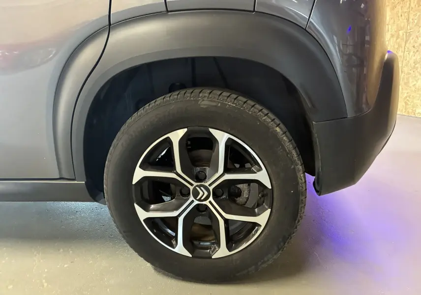 Gros plan sur la roue arrière droite d'un Citroën C3 Aircross gris platinium avec jante alu bi-ton et logo Citroën central.