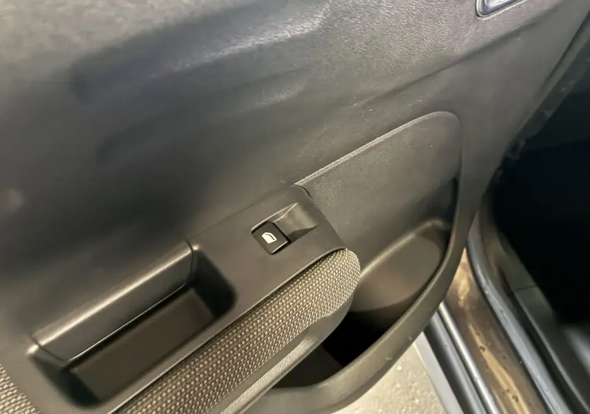 Détail de la commande de lève-vitre sur la portière intérieure côté gauche d'une Citroën C3 Aircross gris platinium.