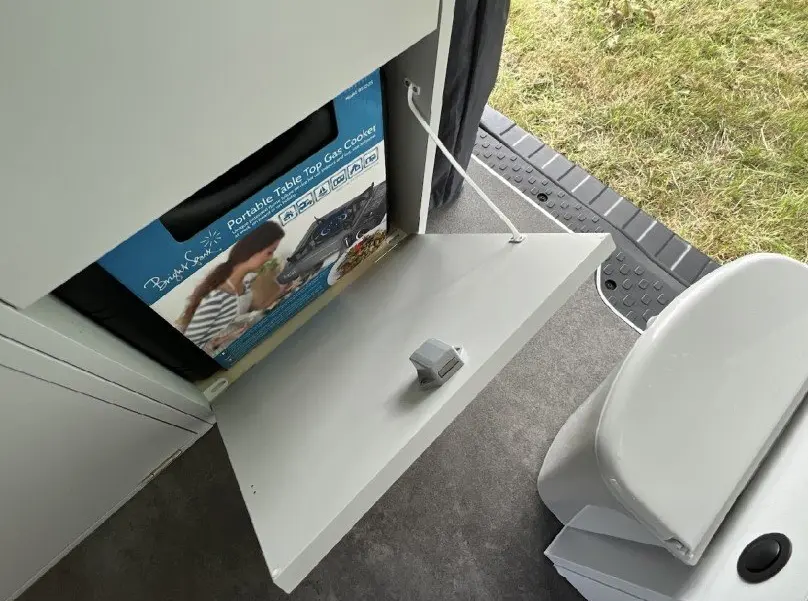 Intérieur du Renault Trafic Fourgon gris, vue sur un espace avec prise électrique et tablette rabattable près d’un siège blanc.