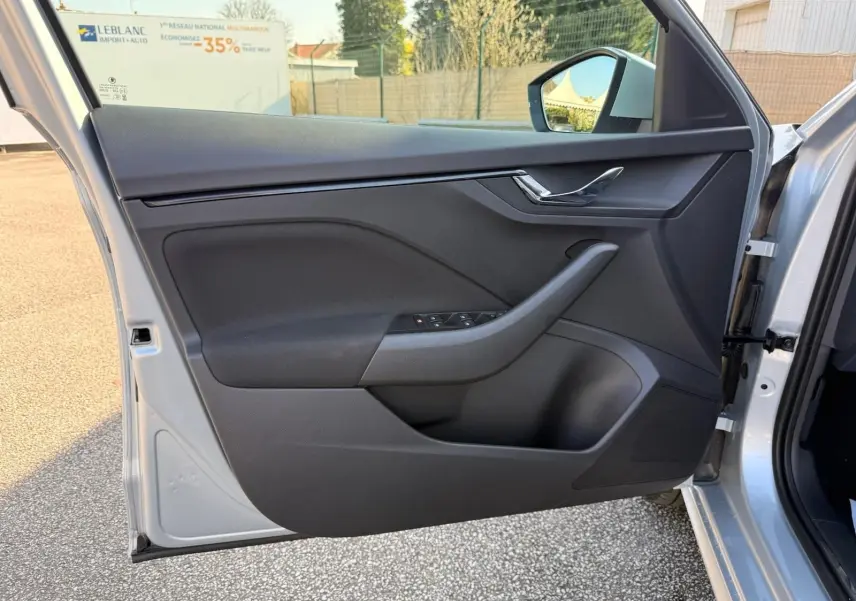 Vue rapprochée de la porte avant gauche gris argent métal d’un Skoda Kamiq 2025, avec commandes de vitres et poignée intégrée.
