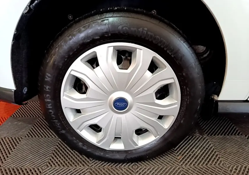 Gros plan sur la roue avant droite blanche du Ford Transit Fourgon avec enjoliveur argenté et logo Ford central.