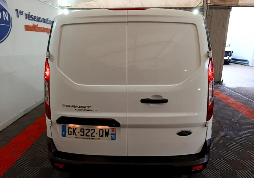 Vue arrière du fourgon blanc Ford Transit Connect 2022 avec portes battantes et feux arrière allumés.
