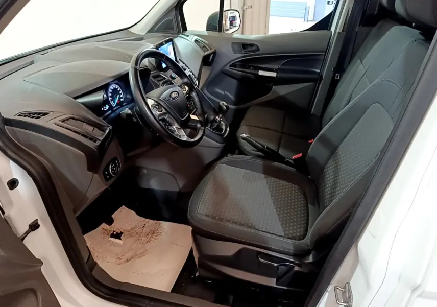 Vue intérieure côté conducteur du Ford Transit Fourgon blanc 2022, montrant le tableau de bord et les sièges avant noirs.