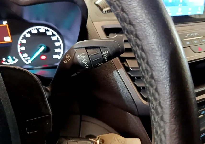 Vue intérieure rapprochée du volant noir et du commodo d’essuie-glace du Ford Transit Fourgon blanc 2022.