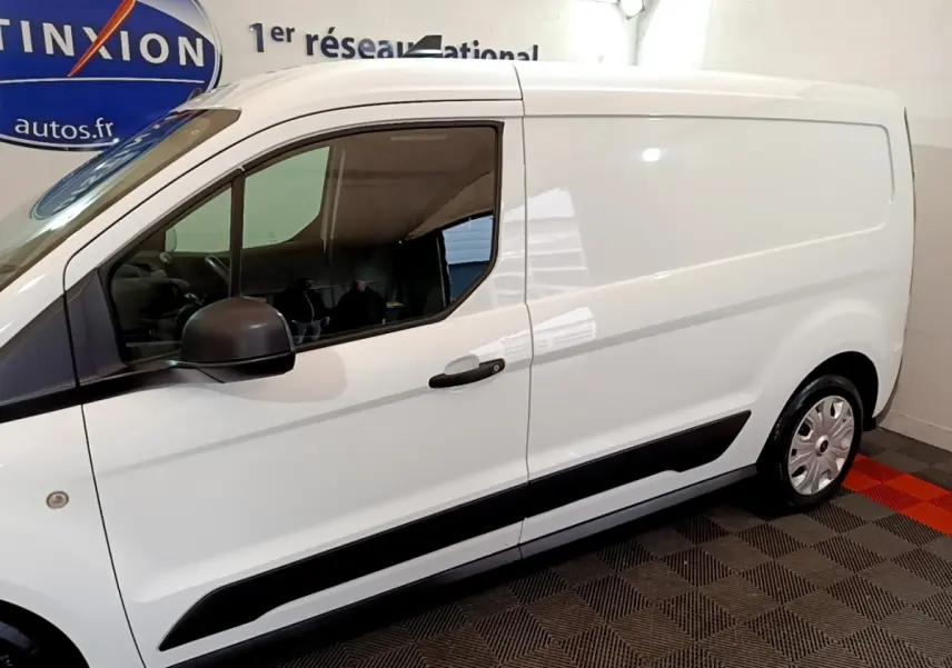 Vue latérale droite d'un fourgon Ford Transit blanc avec rétroviseur noir et protections latérales noires.