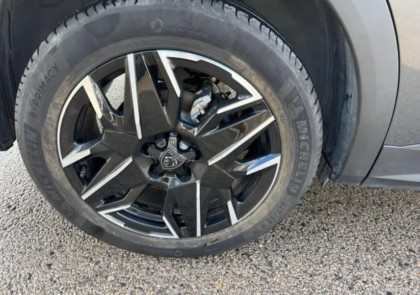 Gros plan sur la jante alliage noire et argent de 19 pouces du Peugeot 3008 Hybrid gris, avec pneu Michelin visible.
