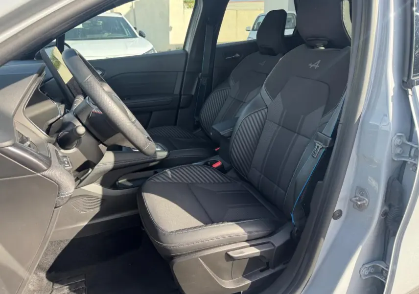 Intérieur avant droit d'une Renault Symbioz gris clair, sièges noirs avec logo Alpine brodé sur les appuie-têtes.