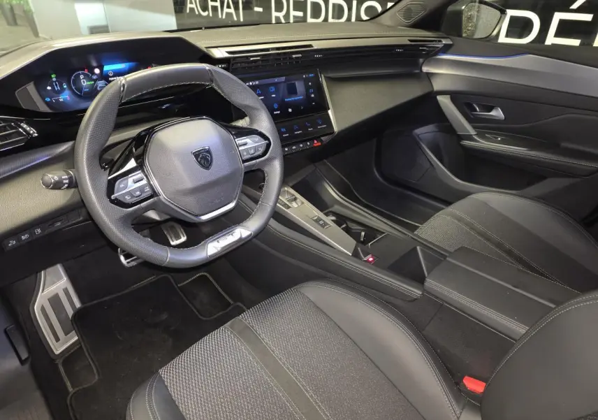Vue intérieure côté conducteur de la Peugeot 408 gris, avec volant cuir perforé et écran tactile central.