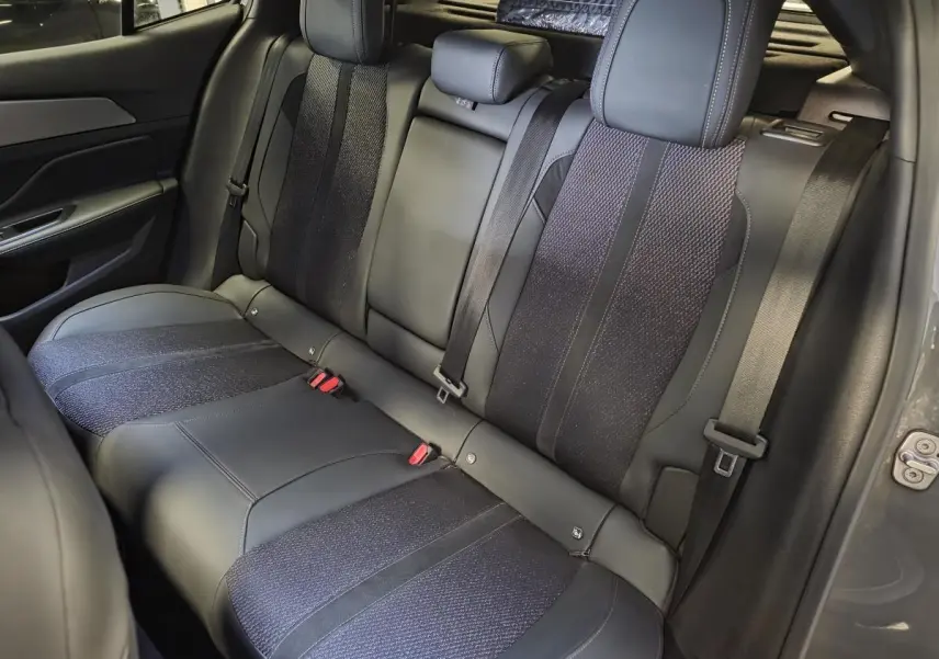 Vue intérieure de la banquette arrière en tissu et cuir noir de la Peugeot 408 gris Selenium, avec ceintures de sécurité visibles.