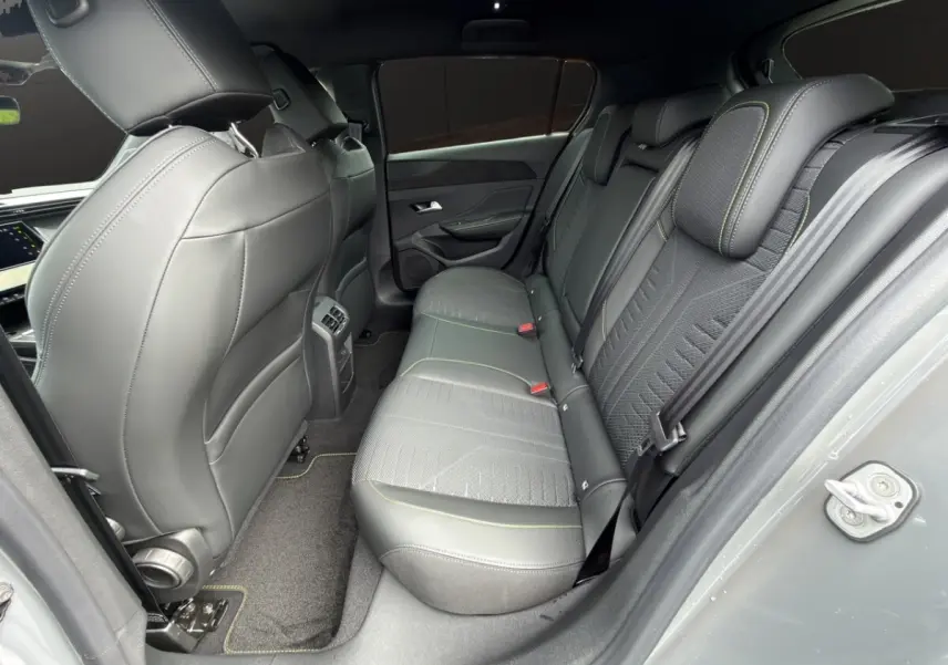 Vue intérieure arrière côté droit de la Peugeot 308 gris clair, sièges en cuir et tissu avec surpiqûres vertes.