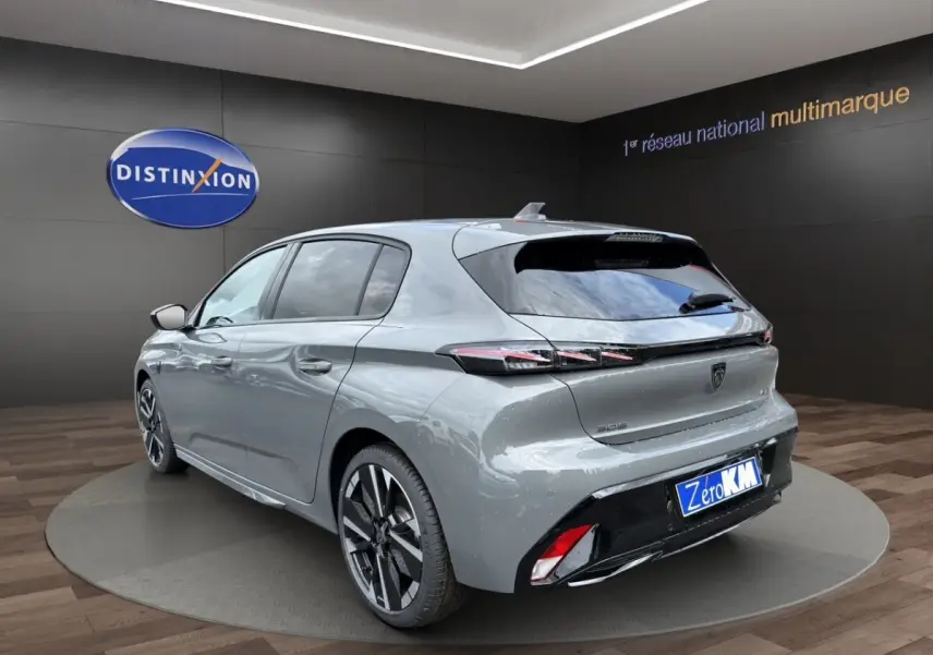 Vue 3/4 arrière droite d'une Peugeot 308 gris clair 2026 avec feux LED et jantes alliage distinctives.