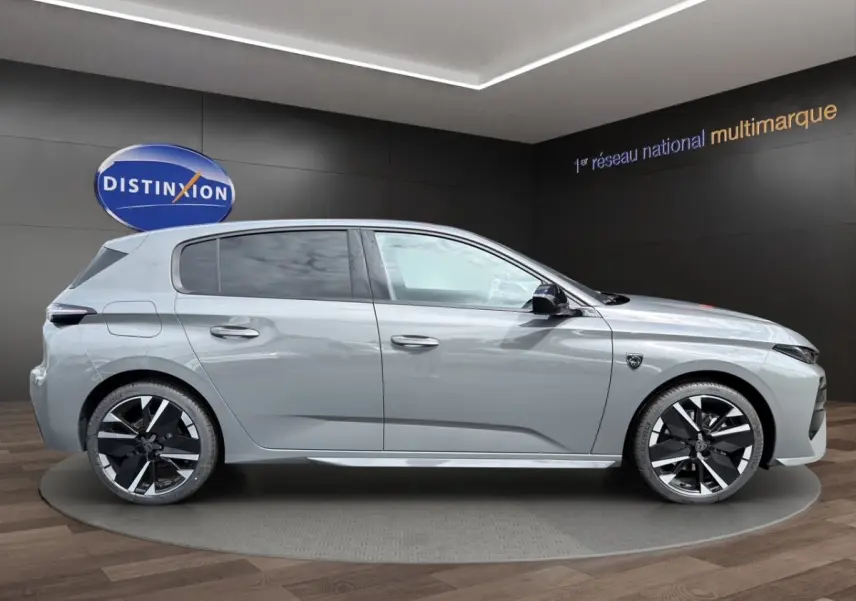 Profil côté droit de la Peugeot 308 GT gris clair 2026 avec jantes noires et détails sportifs visibles.