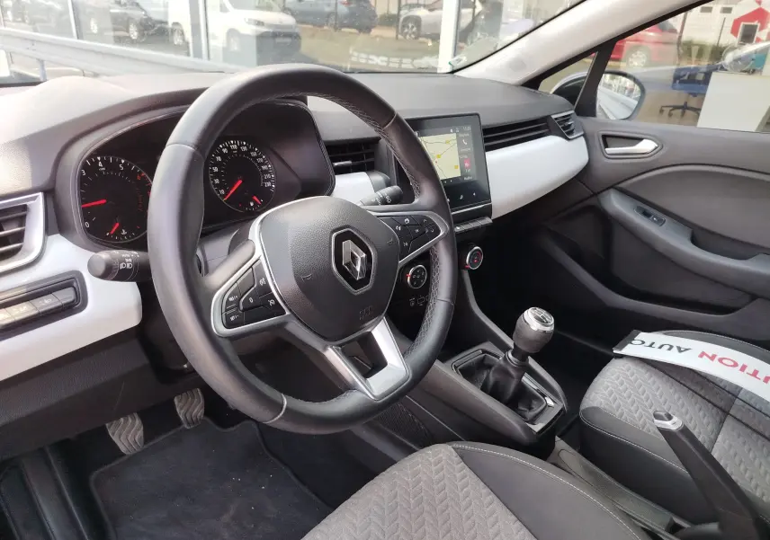 Vue intérieure côté conducteur de la Renault Clio 1.0 SCe 65ch Evolution 2022, volant cuir, tableau de bord moderne et levier de vitesse manuel.