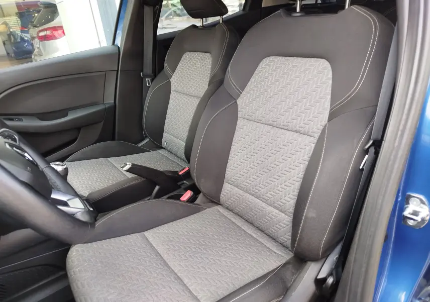 Vue intérieure côté gauche montrant les sièges avant gris et noirs de la Renault Clio Bleu Iron 2022 avec portière ouverte.
