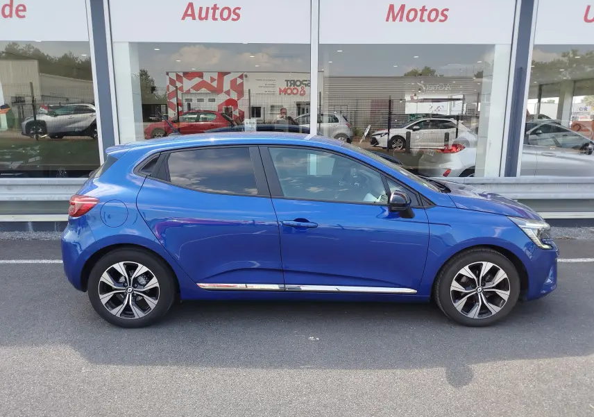 Profil droit d'une Renault Clio 1.0 SCe 65ch Evolution 2022 en Bleu Iron avec jantes alliage bicolores et vitres teintées.