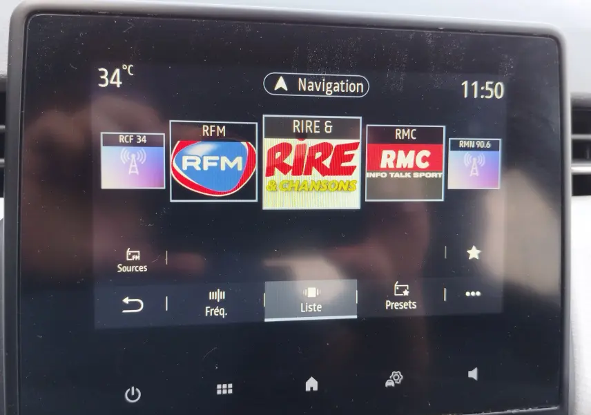 Écran tactile central de la Renault Clio 2022 affichant les stations radio avec interface moderne et température à 34°C.