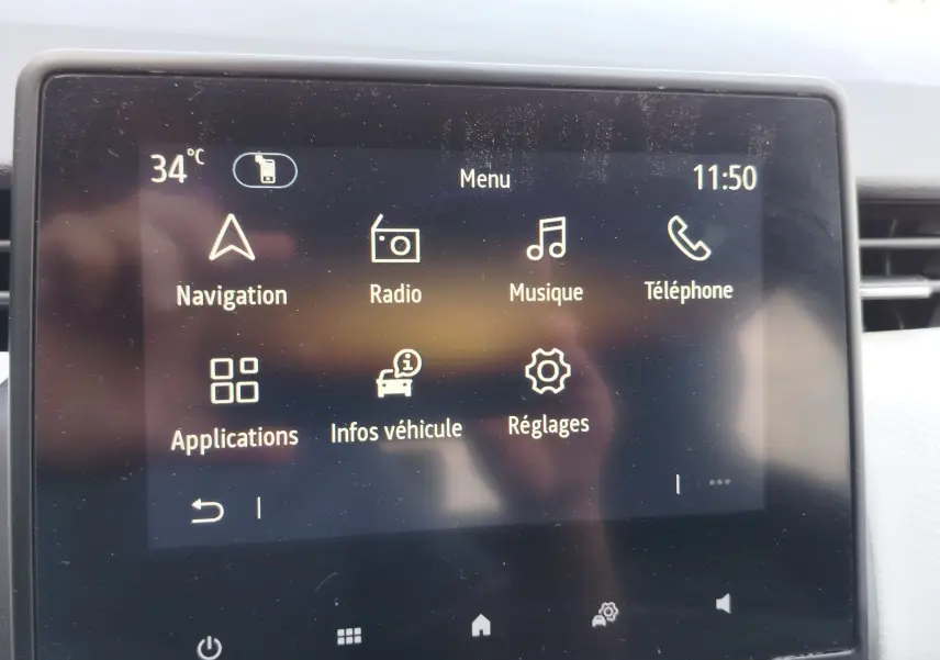 Écran tactile central de la Renault Clio 2022 affichant le menu principal avec navigation, radio, musique et téléphone.