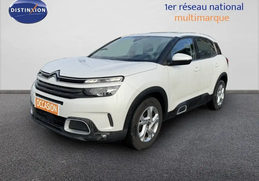 Vue 3/4 avant d'un Citroën C5 Aircross blanc nacré avec détails noirs et jantes argentées sur fond neutre.