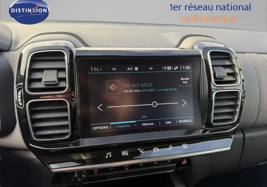 Écran tactile central allumé avec radio FM, entouré de deux aérateurs noirs sur tableau de bord gris du Citroën C5 Aircross.