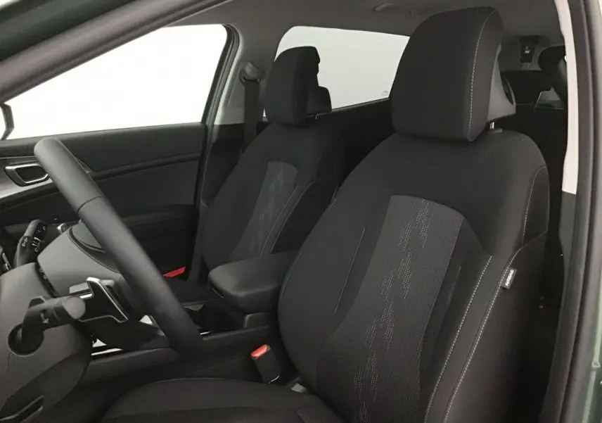 Vue intérieure côté conducteur du Kia Sportage 2025, sièges en tissu noir avec surpiqûres contrastantes.