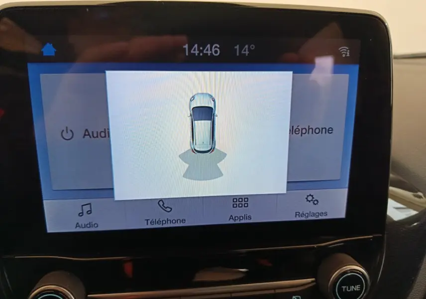 Écran tactile central du Ford Puma montrant la vue aérienne du véhicule blanc en stationnement.