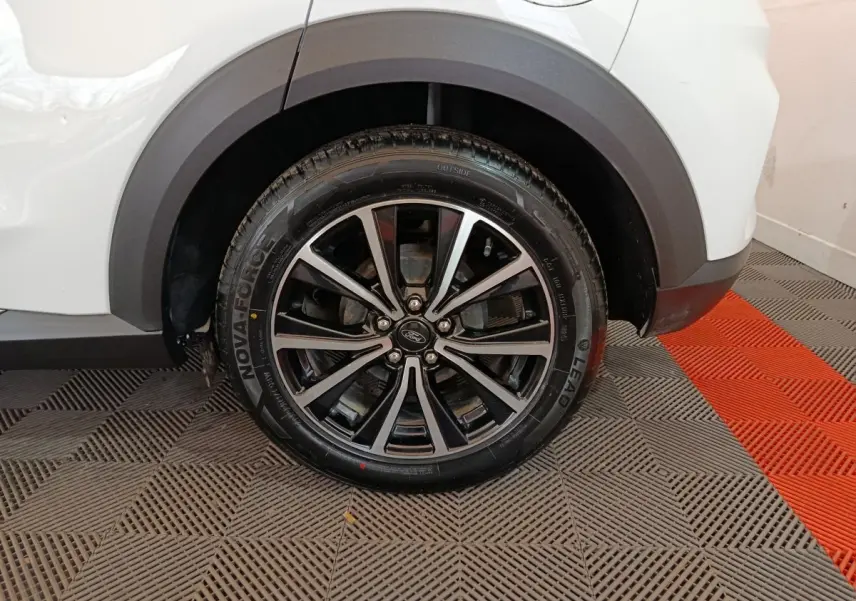 Gros plan sur la roue arrière droite avec jante alliage noir et argent du Ford Puma blanc 2022.