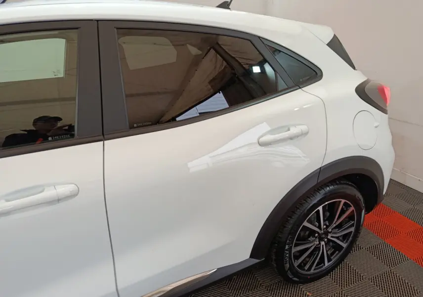 Vue côté droit arrière du Ford Puma blanc 2022 avec jantes alliage et protections noires sur les passages de roues.