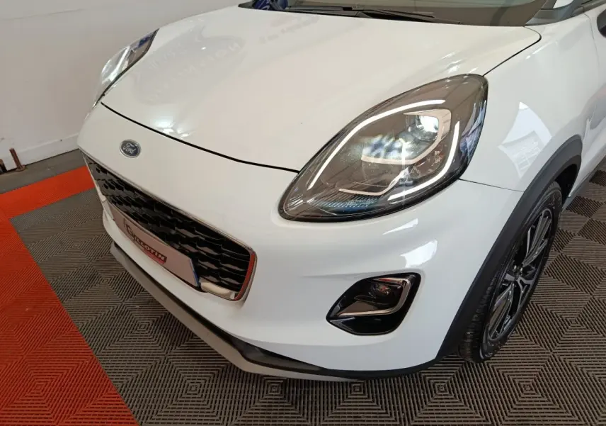 Vue 3/4 avant droit d'une Ford Puma blanche avec phares LED et calandre noire brillante.