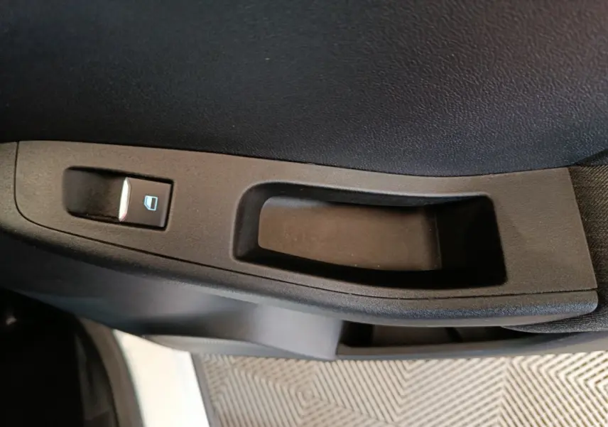 Gros plan sur la commande de lève-vitre côté conducteur d'une Ford Puma blanche, intérieur noir.