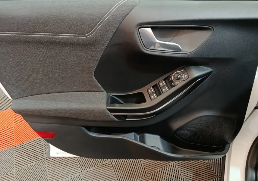 Vue rapprochée de la porte avant gauche blanche du Ford Puma 2022, montrant les commandes de vitres et la poignée intérieure.