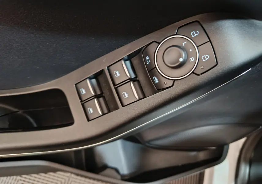 Gros plan sur les commandes de lève-vitres et rétroviseurs côté conducteur du Ford Puma blanc 2022.