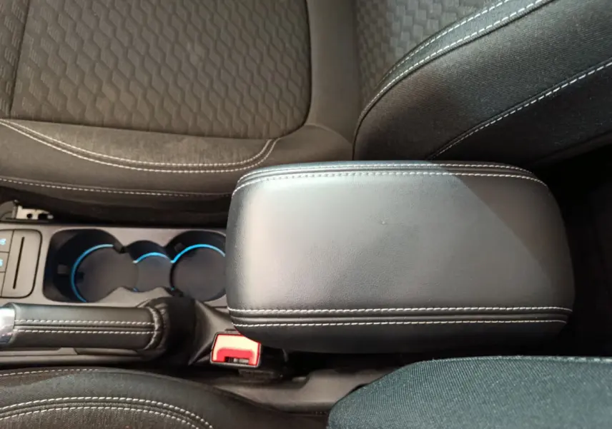 Vue rapprochée de l'accoudoir central noir et des sièges tissu gris foncé avec surpiqûres blanches dans une Ford Puma 2022.