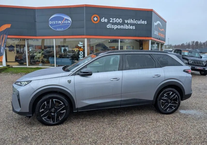 Vue de profil côté gauche d’un Peugeot 5008 gris métallisé 2025 avec jantes alliage noires et toit noir.