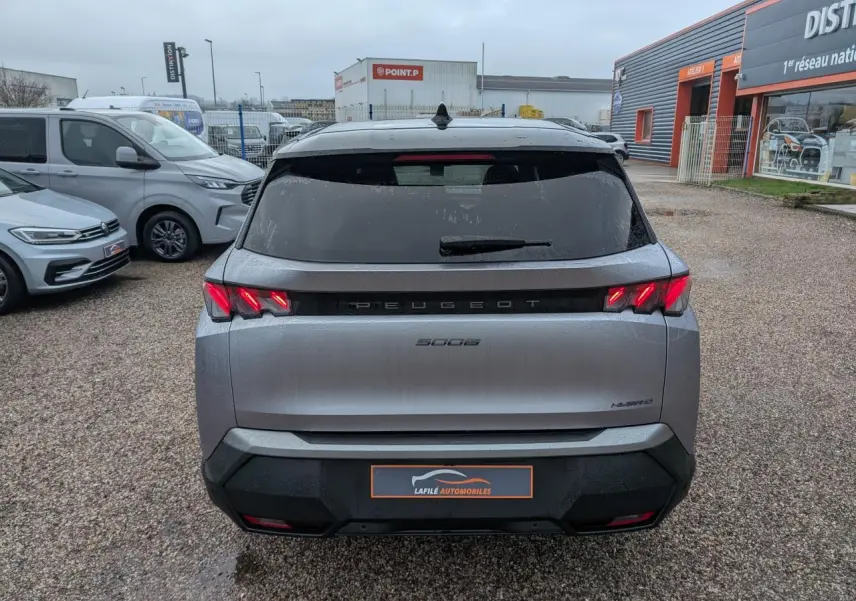 Vue arrière d'un Peugeot 5008 gris métallisé 2025 avec feux arrière 3 griffes LED et bandeau noir laqué entre les feux.