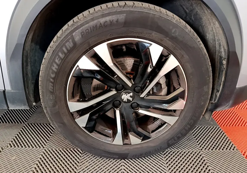 Gros plan sur la roue avant droite du Peugeot 2008 gris clair, avec jante alliage noire et argentée distinctive.