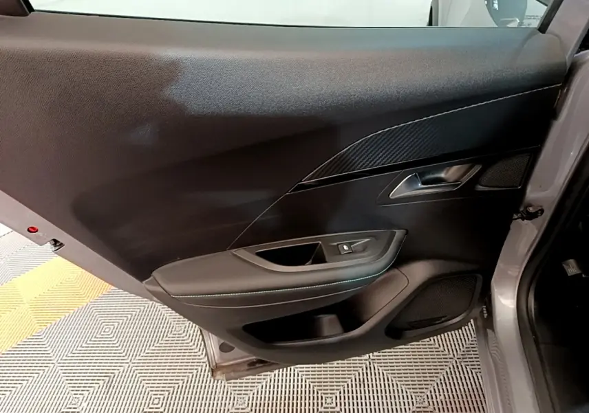 Vue intérieure de la porte arrière gauche gris clair du Peugeot 2008 avec garniture noire et poignée métallique.