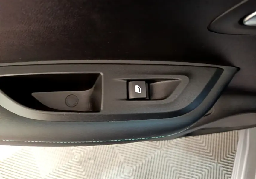 Gros plan sur la commande de lève-vitre côté gauche intérieur d’un Peugeot 2008 gris clair de 2021.